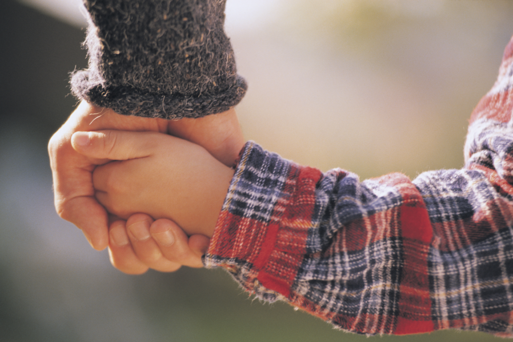 Image of a child holding an adult's hand for a blog about appointing a guardian in your will